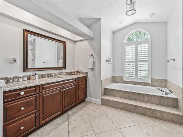 a spacious bathroom with a granite countertop sink a mirror and a shower