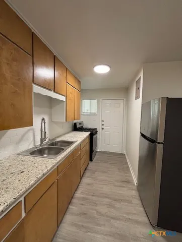 a large kitchen with granite countertop a refrigerator and a sink