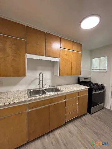 a kitchen with stainless steel appliances granite countertop a sink and a stove next to a window