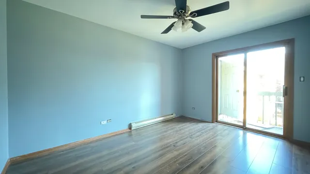 an empty room with wooden floor fan and windows