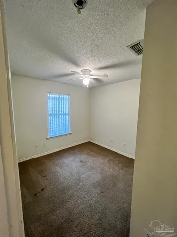 an empty room with windows and fan
