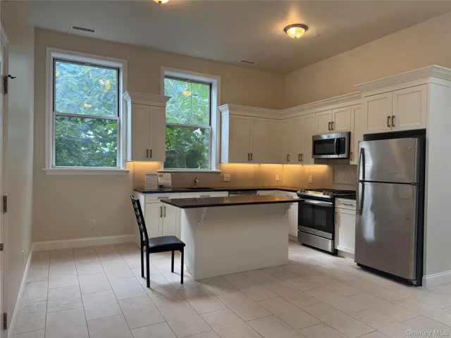 a kitchen with kitchen island a counter top space cabinets and stainless steel appliances