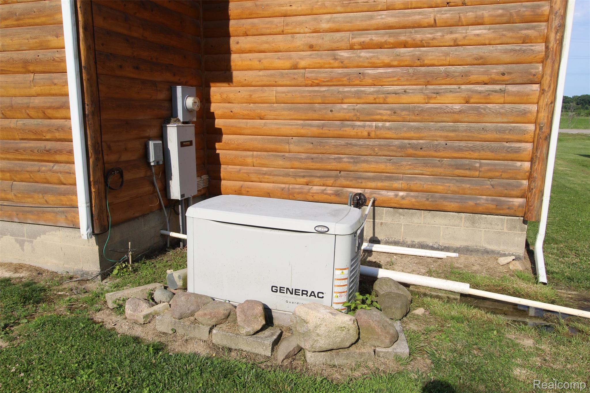2568 Valentine Road Lapeer, MI 48446 - Photo 39 of 42 Standby generator system with weatherproof enclosure, positioned on a decorative stone pad