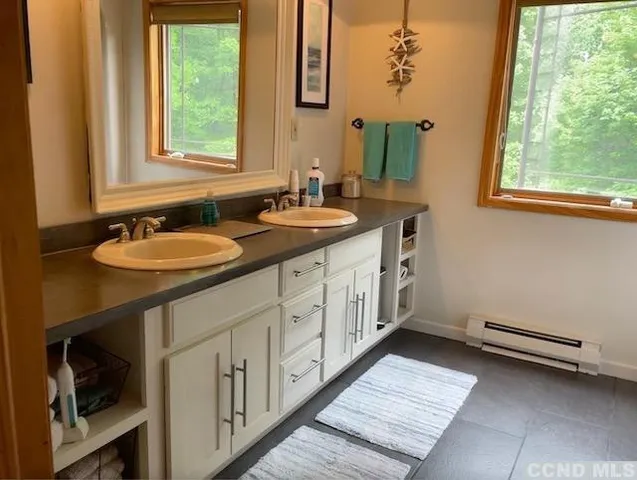 a bathroom with a granite countertop sink and a window