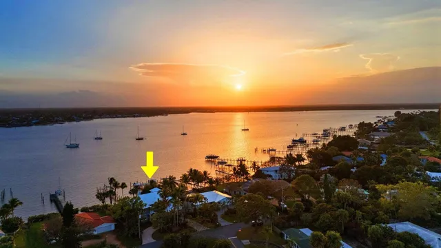 a view of a house with a big yard and palm trees