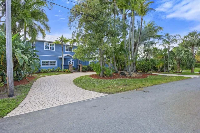 a kitchen with stainless steel appliances kitchen island granite countertop a refrigerator a stove a sink a dining table and chairs with wooden floor