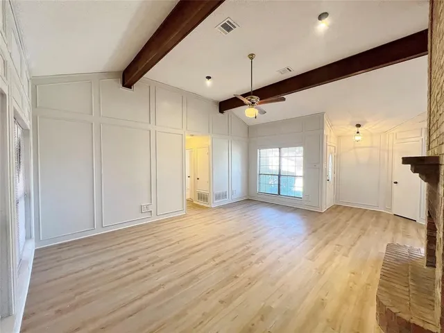 a view of empty room with wooden floor and fireplace