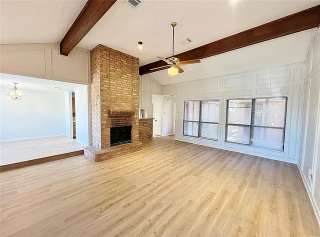 an empty room with wooden floor and fireplace