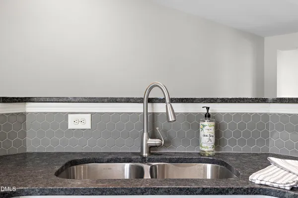a kitchen with a sink a stove cabinets and a wooden floor