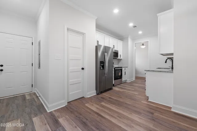 a view of a kitchen with refrigerator and wooden floor