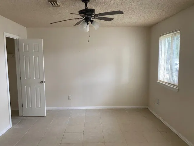 an empty room with a window and a fan
