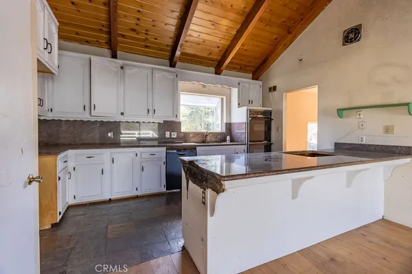 a kitchen with granite countertop a sink a stove and cabinets