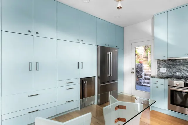 a kitchen with stainless steel appliances kitchen island granite countertop a refrigerator a stove and white cabinets with wooden floor