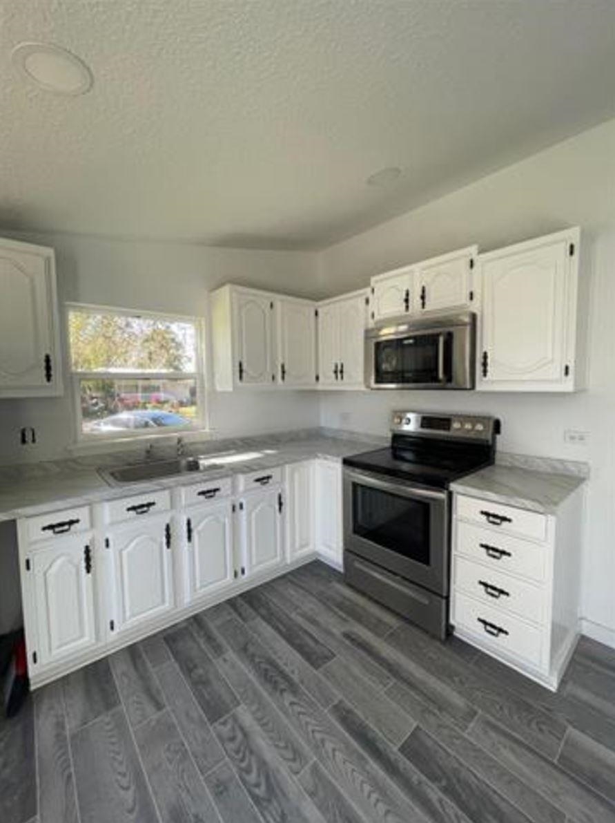 1442 Spring Street St. Augustine, FL 32084 - Photo 4 of 7 a kitchen with granite countertop white cabinets appliances a sink and a window