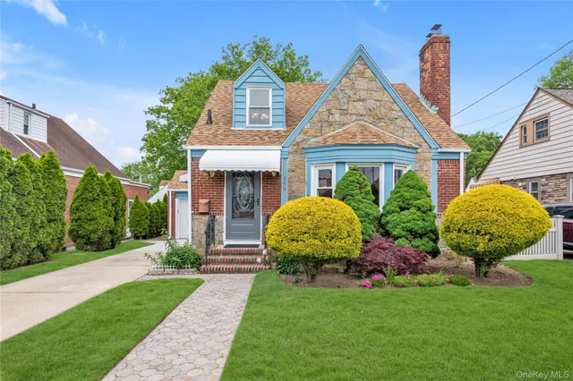 a view of brick house with a yard potted plants and a large tree