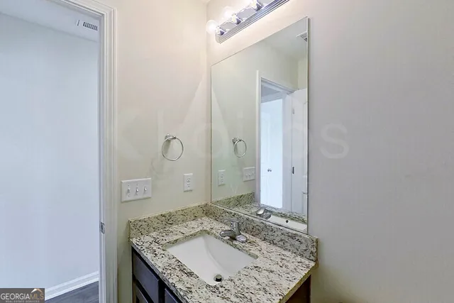a bathroom with a granite countertop sink and a mirror