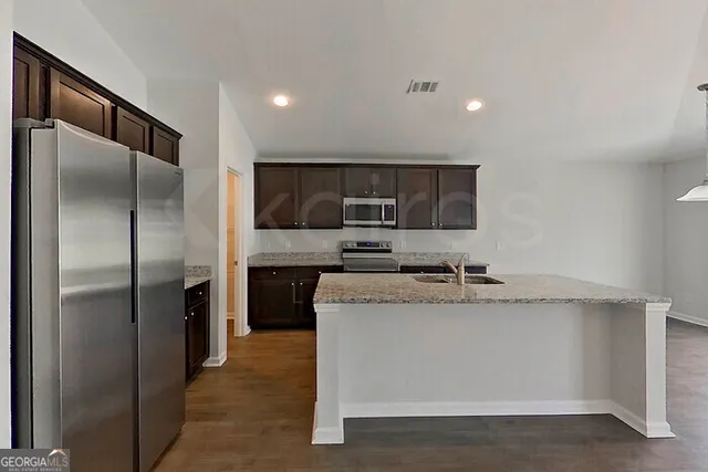 a kitchen with stainless steel appliances granite countertop a refrigerator a sink and a stove