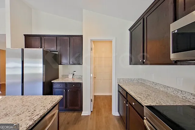 a kitchen with granite countertop a oven a refrigerator and wooden floor