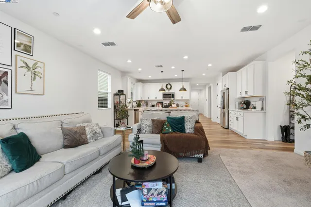a living room with furniture kitchen view and a chandelier