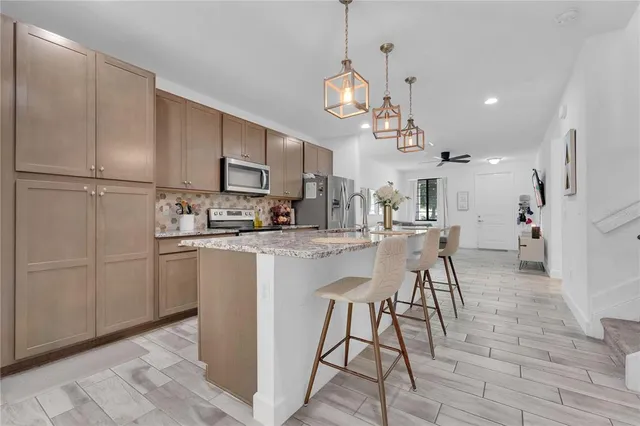 a kitchen with stainless steel appliances kitchen island granite countertop a sink a microwave a refrigerator and white cabinets