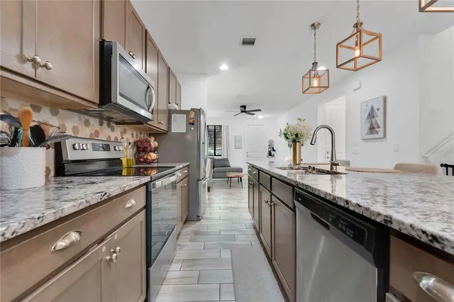 a large kitchen with stainless steel appliances granite countertop a sink stove and refrigerator