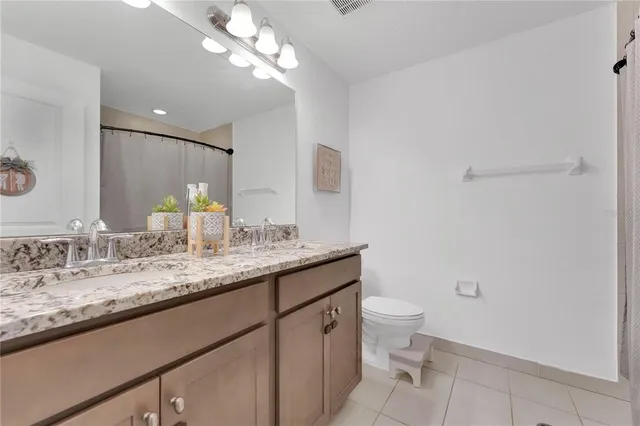 a bathroom with a granite countertop sink a toilet and a mirror