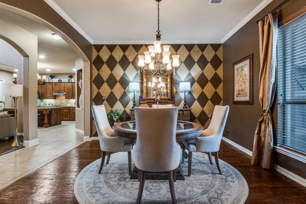 2810 Baker Street Sachse, TX 75048 - Photo 10 of 26 Dining space with an accent wall, arched walkways, ornamental molding, a chandelier, and dark wood finished floors