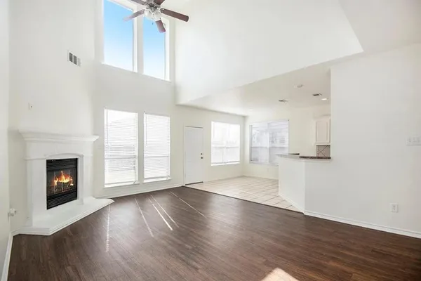an empty room with wooden floor fireplace and windows