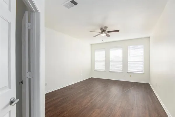 an empty room with wooden floor and ceiling fan