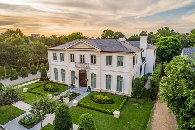 a view of a white house with a big yard and potted plants