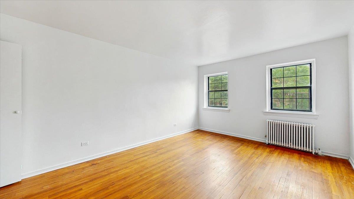 144-15 78th Road, Unit 3A Queens, NY 11367 - Photo 4 of 26 Unfurnished room featuring radiator heating unit and light wood finished floors