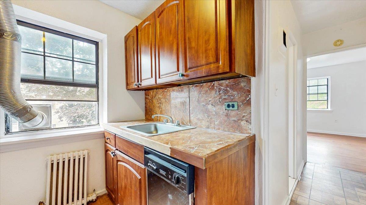 144-15 78th Road, Unit 3A Queens, NY 11367 - Photo 10 of 26 Kitchen featuring radiator heating unit, black dishwasher, tasteful backsplash, and brown cabinets
