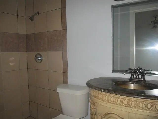 a bathroom with a granite countertop sink a toilet and shower
