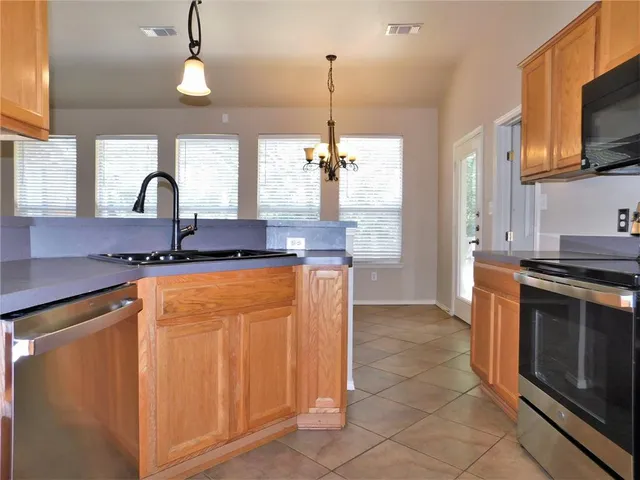 a kitchen with stainless steel appliances granite countertop a stove a sink and a microwave