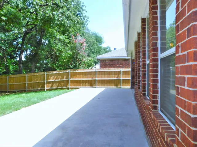 a view of a backyard with brick wall and a large tree