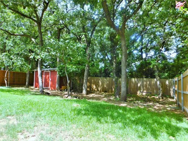 a view of a backyard with table and chairs and a large tree
