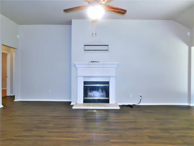 a view of an empty room with wooden floor fireplace and a window