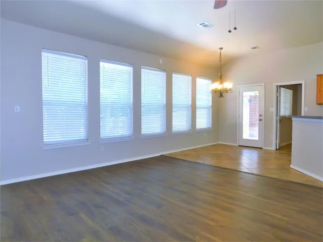a view of an empty room with window and wooden floor