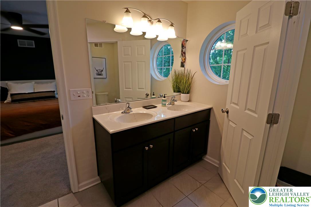 4502 Benjamin Court Emmaus, PA 18049 - Photo 29 of 53 Dual vanity with bright lighting complements the clean, tiled floor in this inviting primary bathroom.