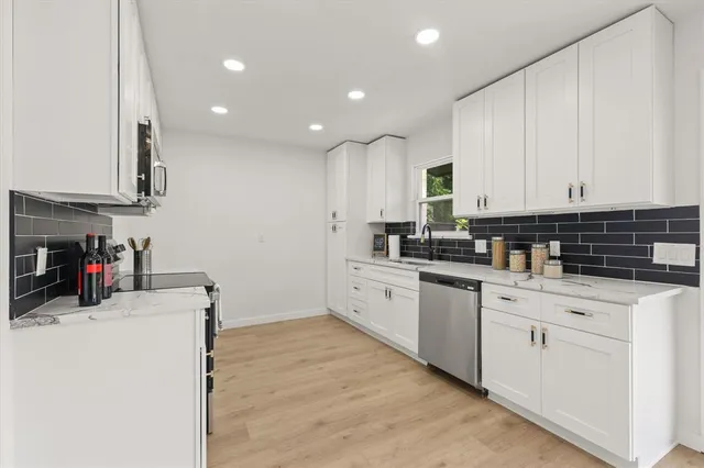 a kitchen with stainless steel appliances granite countertop a stove and white cabinets