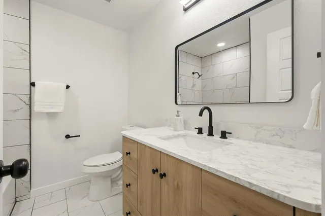 a bathroom with a granite countertop sink a toilet and mirror