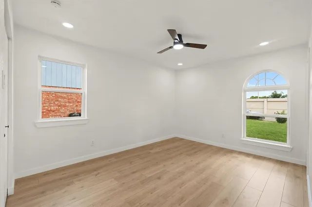 an empty room with a window and ceiling fan