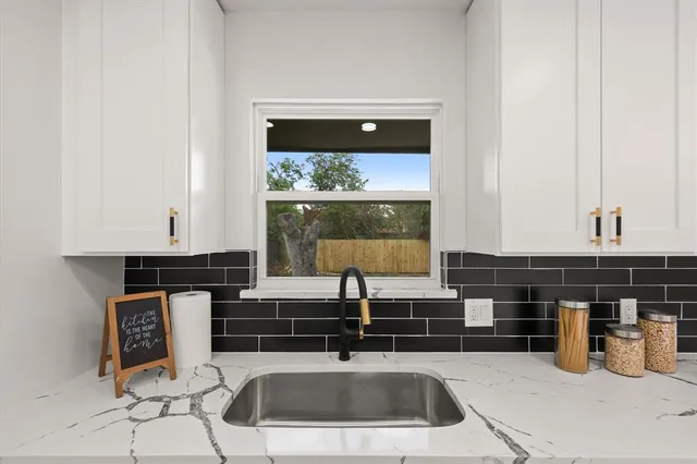 a kitchen with stainless steel appliances a sink a stove and white cabinets