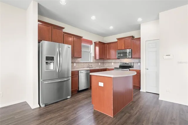 a large kitchen with stainless steel appliances kitchen island a large counter top and a wooden floors