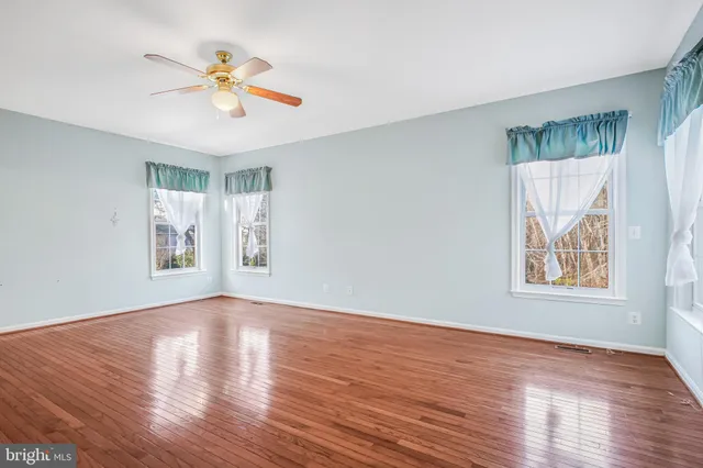 a view of an empty room with wooden floor and window