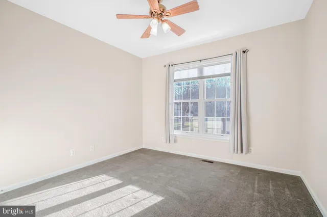 an empty room with chandelier fan and windows