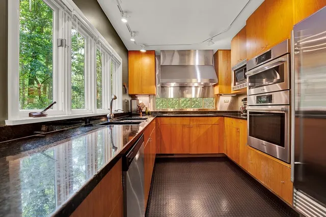 a kitchen with stainless steel appliances granite countertop a sink a stove and a refrigerator
