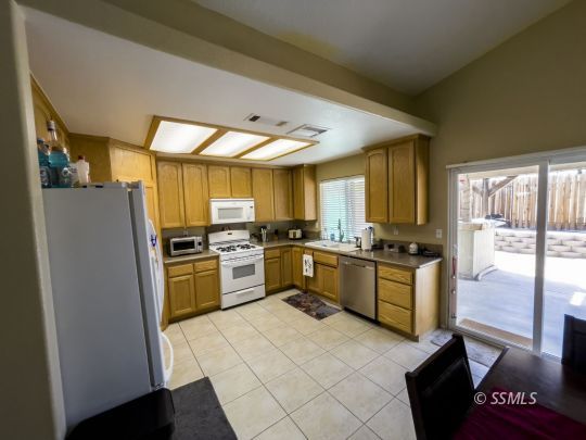 1411 Sims Street Ridgecrest, CA 93555 - Photo 7 of 35 a kitchen with a refrigerator a stove top oven a sink and dishwasher