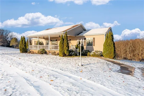 a view of white house with a big yard and large trees