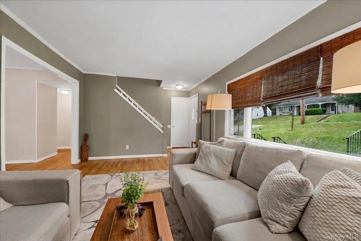 10 Susquehanna Road Ossining, NY 10562 - Photo 4 of 31 Spacious living area featuring expansive windows with bamboo shades, wood-finish flooring, and a visible staircase